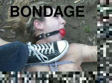 BDSM slut tied up in the dirt and gagged as part of fetish games