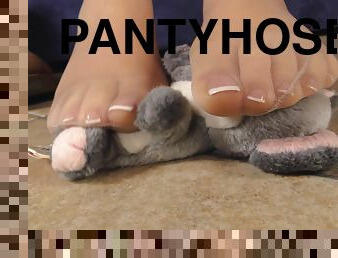Sexy feet in sheer pantyhose play with a stuffed animal