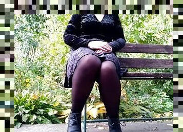 Peeing with legs spread wide on a bench in an autumn park