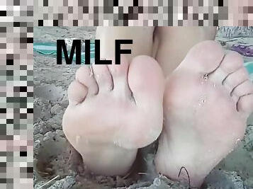 MILF teases you with her miniature feets on the beach, playing with them in the sand and the sea.
