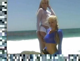 Blonde chicks in fishnet shirts play with their pussies on a beach