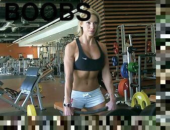 A pretty blonde in sportswear shows her boobs in a gym