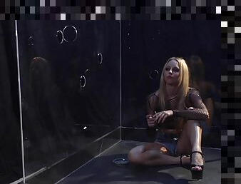 A blonde in bodystockings sucks a dick sitting in a glass box