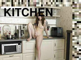 Redhead Sonya Blake in tattoo caresses her pussy in the kitchen