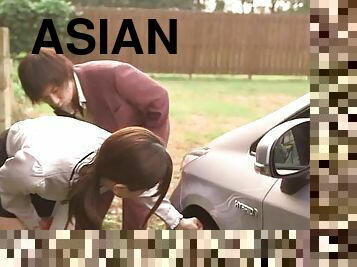 A wild Asian couple fucking in the back of a car outdoors