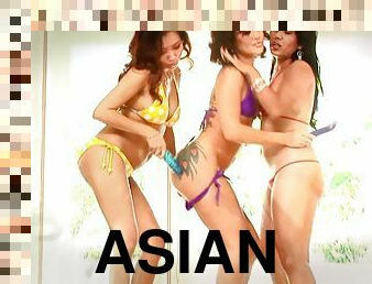 Three Asian lesbians wearing bikinis use dildos to please each other