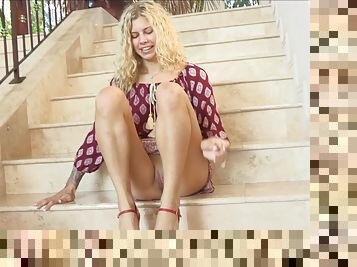 A beautiful blonde with red heels sits on stairs and ram her pussy using one of the heels