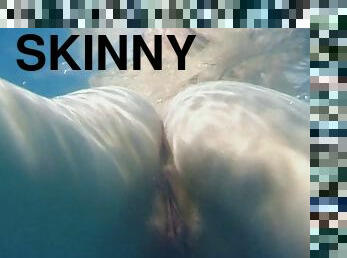 Skinny dipping teens play in the pool and finger underwater