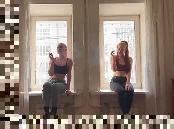 Two girls are smoking on the window