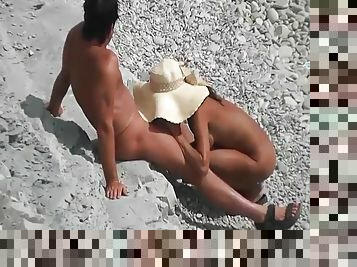 Girl in a big hat sucks cock on the beach