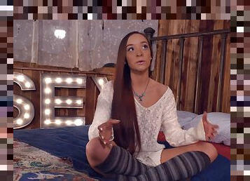 Long-haired sweet thing Jessie Lynne sits on her bed wearing leggings