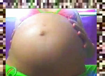 A pregnant brunette is clad in skimpy neon bikini and flashing her big momma tits