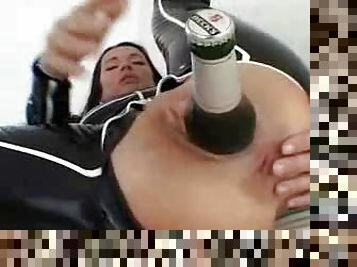 Bottle of beer inside the latex girl's ass