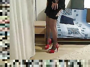MILF tranny showing off and touching in front of the camera wearing a black satin dress, fishnet stockings and heels