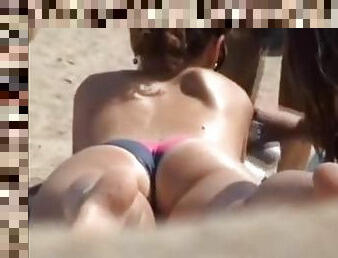 Two sexy chicks lie topless at the beach not realizing that they're filmed