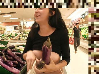 Darh haired Lexi has fun with vegetables in a public store